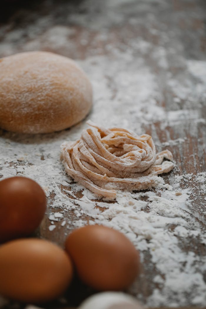 From above of noodle and dough among eggs prepared for cooking tasty pasta